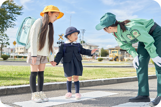 横断歩道で児童の誘導をする警備員